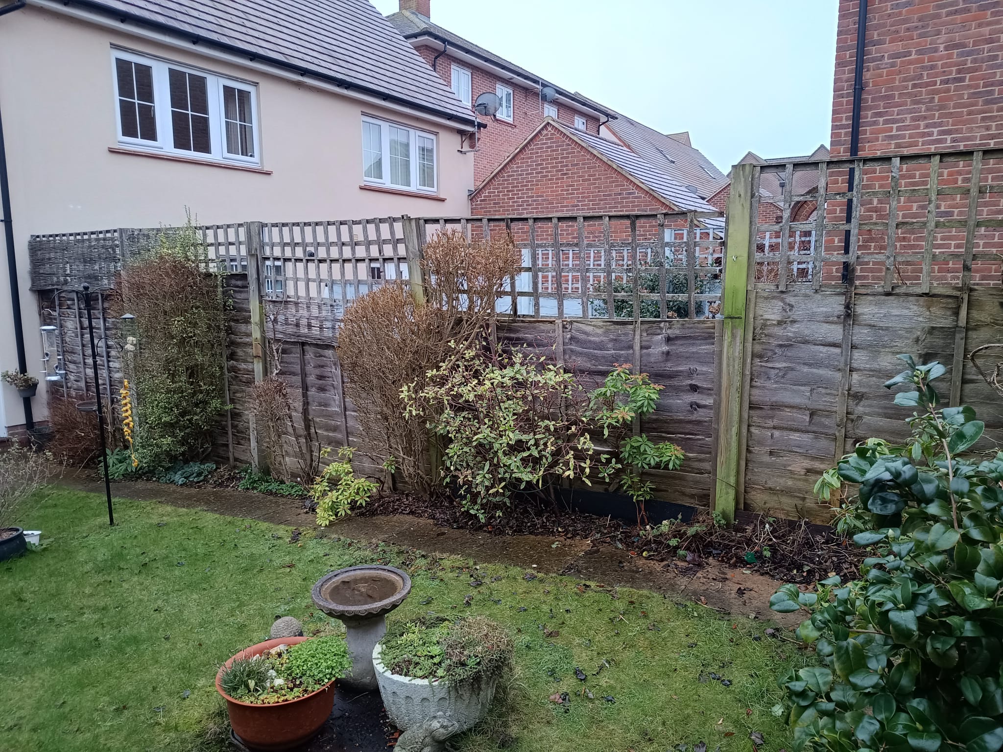 Old weathered lap fence with broken trellis before replacement